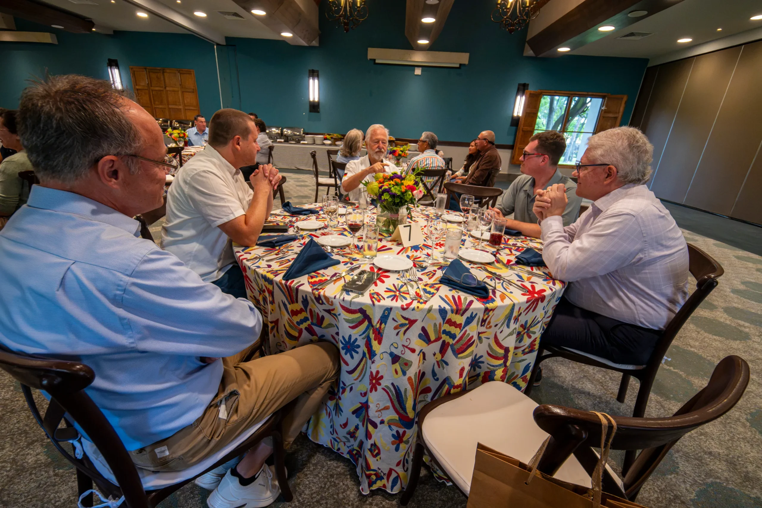 Grupo de hombres conversando alrededor de una mesa redonda durante una comida de networking en un evento empresarial.